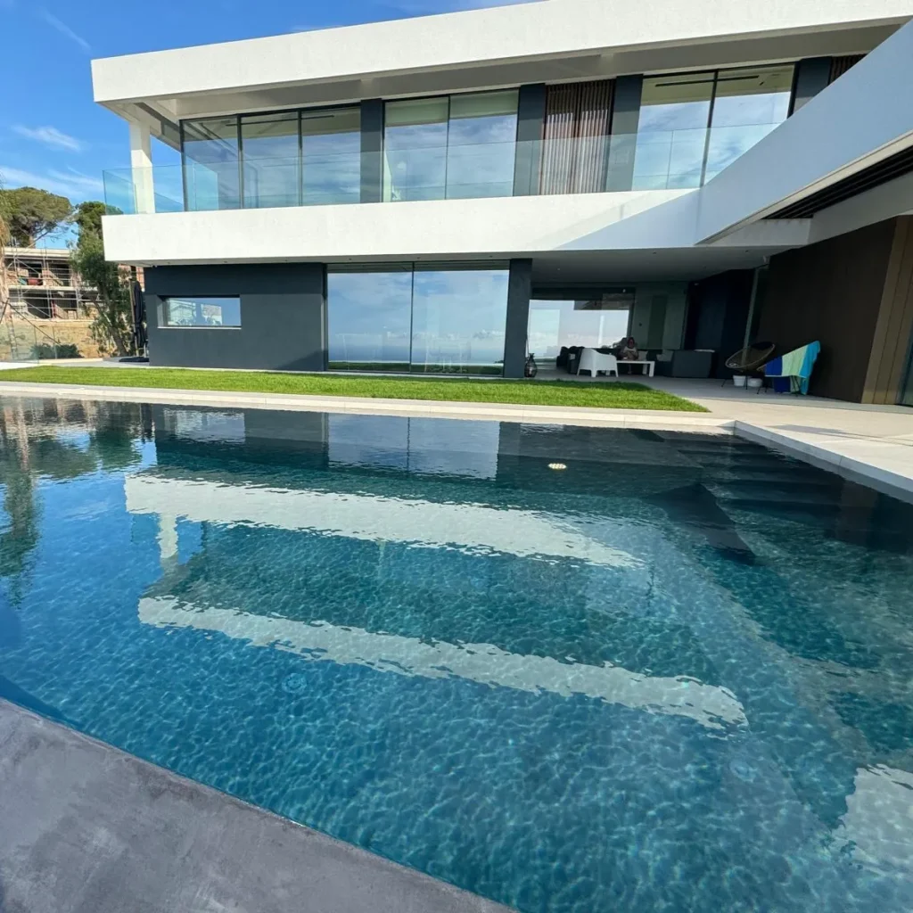Surface de l’eau parfaitement lisse reflétant la façade vitrée de la maison contemporaine