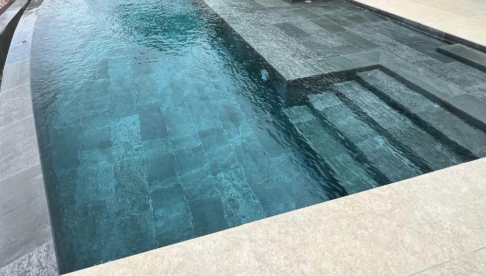 Vue de l'accès dans une piscine à débordement par plage immergée et escalier