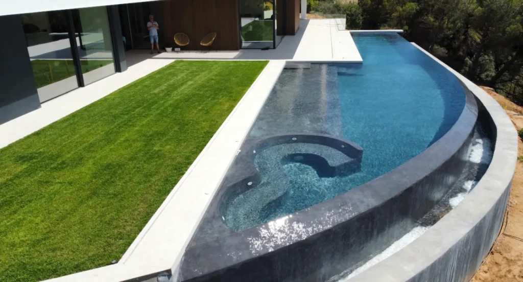Vue plongeante sur piscine à déborement ruisselant et jacuzzi intégré