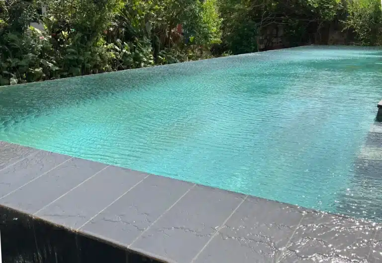 Piscine à débordement en cascade avec finitions pierre naturelle dans villa moderne a Lomé