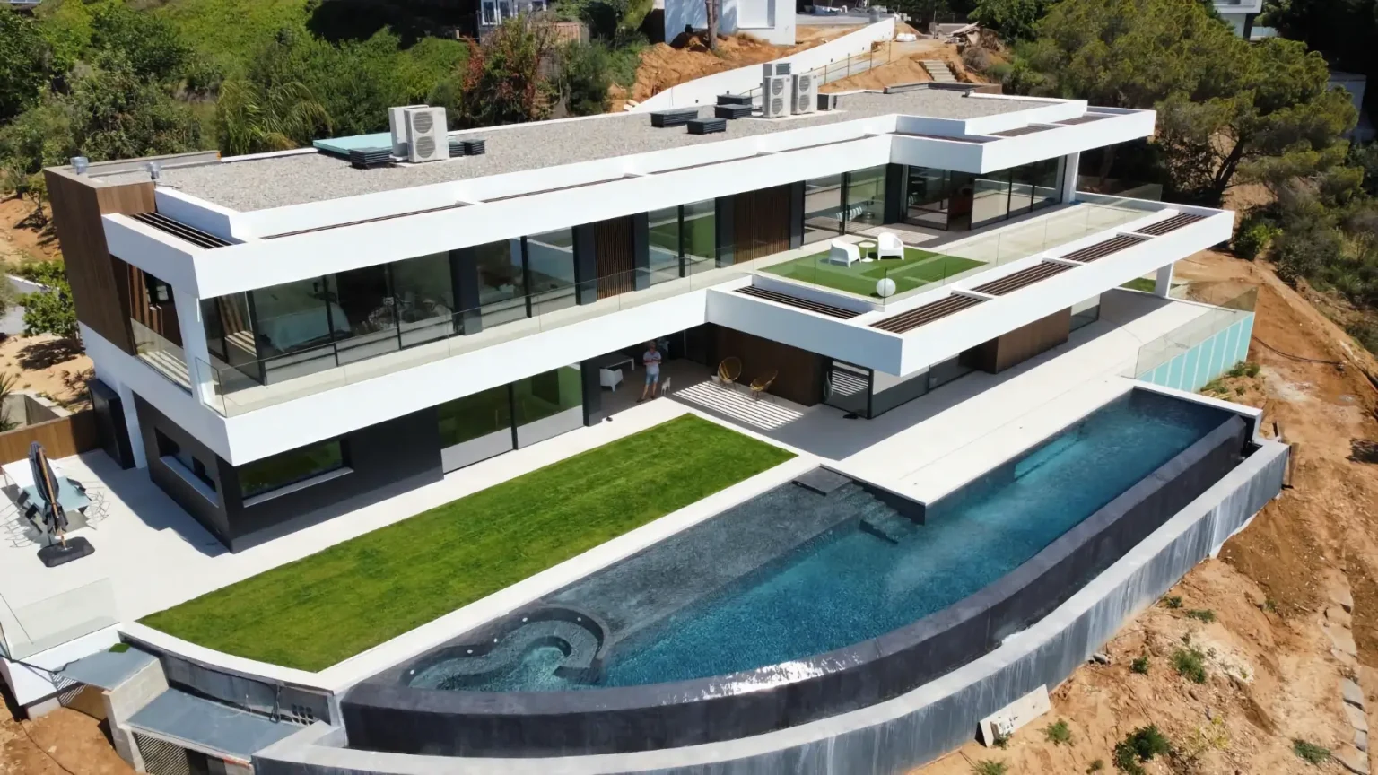 Vue aérienne d'une piscine à débordement en Catalogne, intégrée à une villa contemporaine avec panorama sur les collines de la région de Barcelone