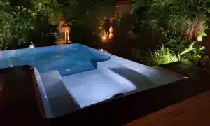 Coin spa d’une piscine contemporaine illuminé de nuit, entouré de végétation luxuriante au Togo