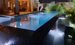 Piscine à débordement moderne éclairée la nuit au Togo avec vue sur terrasse et salon