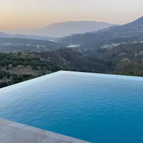 Piscine à débordement intégrée à un terrain en pente, exemple d’architecture de piscine en continuité avec le paysage naturel.