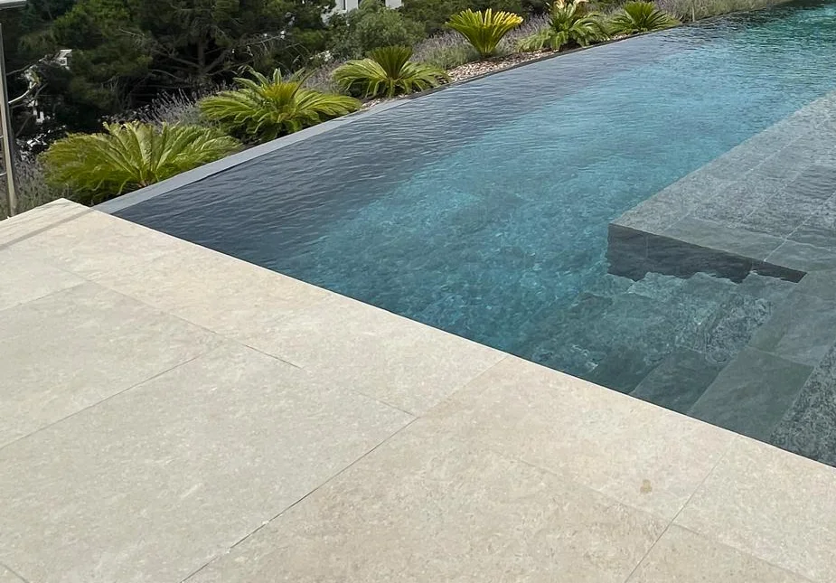 Photo montrant la precesion nécessaire pour la pose de pierre naturelle dans une psicine à débordement