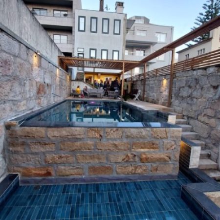 Piscine à débordement semi-enterrée avec parement en pierre, intégrée dans un jardin urbain étroit à Porto